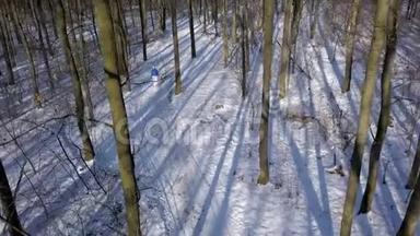 从高处到穿着温暖衣服的女人，在美丽的冬季白雪覆盖的风景中漫步在一条小径上。 清楚